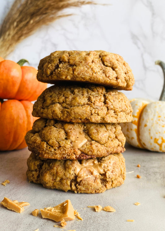Stack of pumpkin cookies with pumpkins and a decorative bag in the background