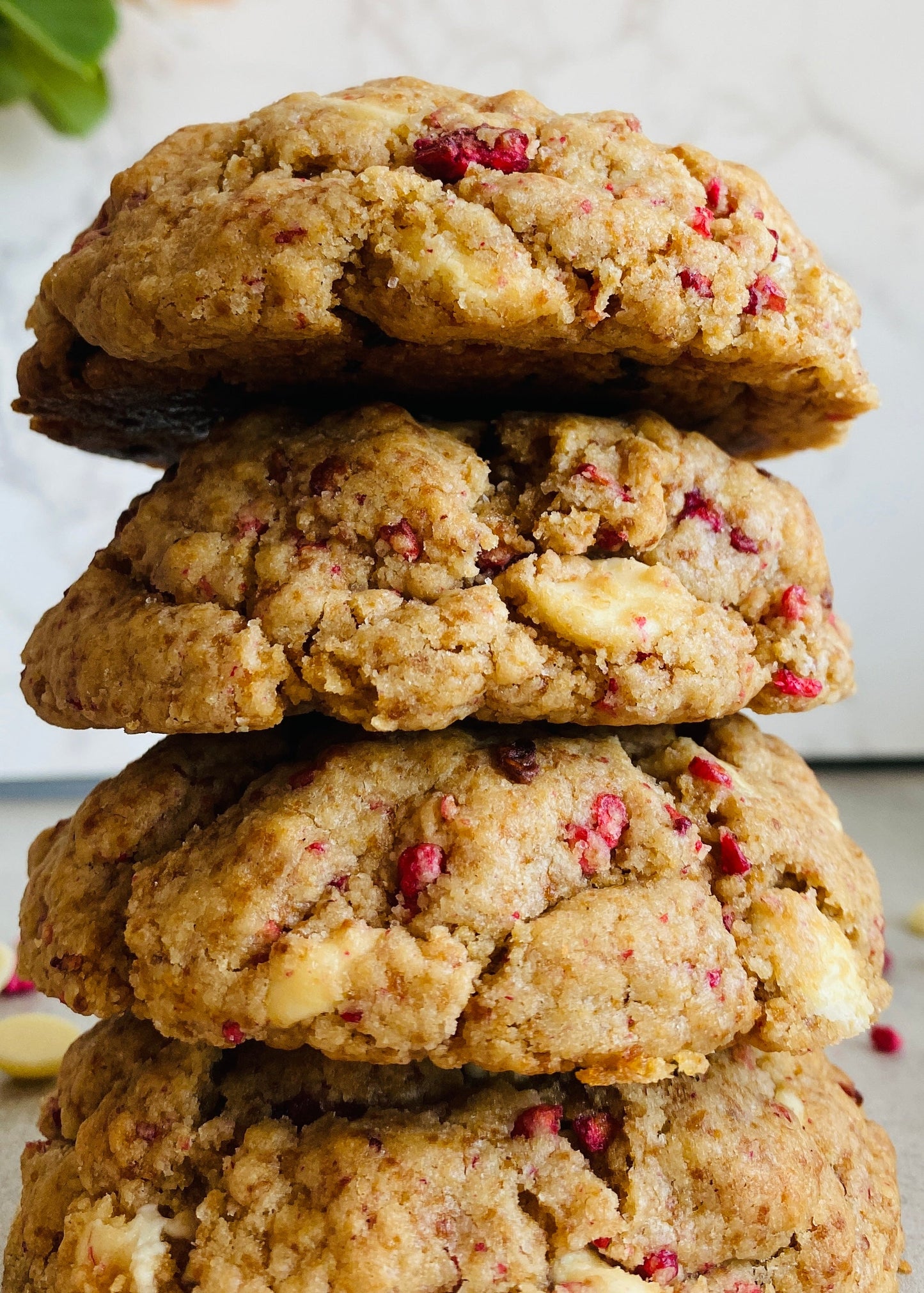 Stack of cookies with white chocolate chips and raspberries on a light background