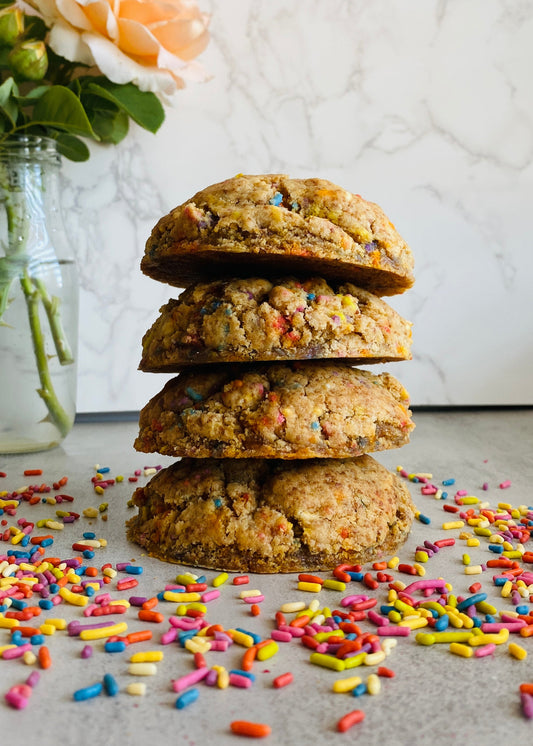 Stack of cookies with colorful sprinkles on a light surface, with a blurred background