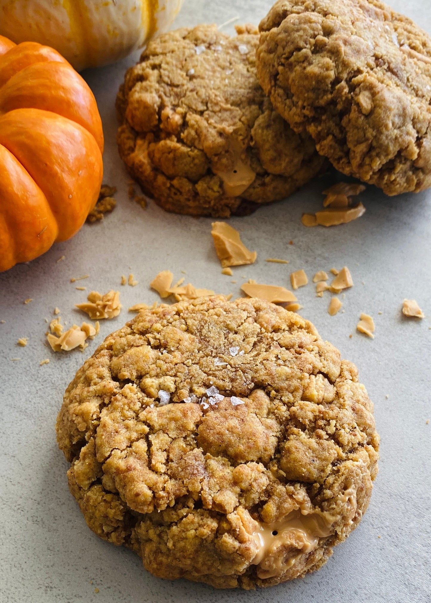 Pumpkin cookies with a few pieces of pumpkin on a gray surface