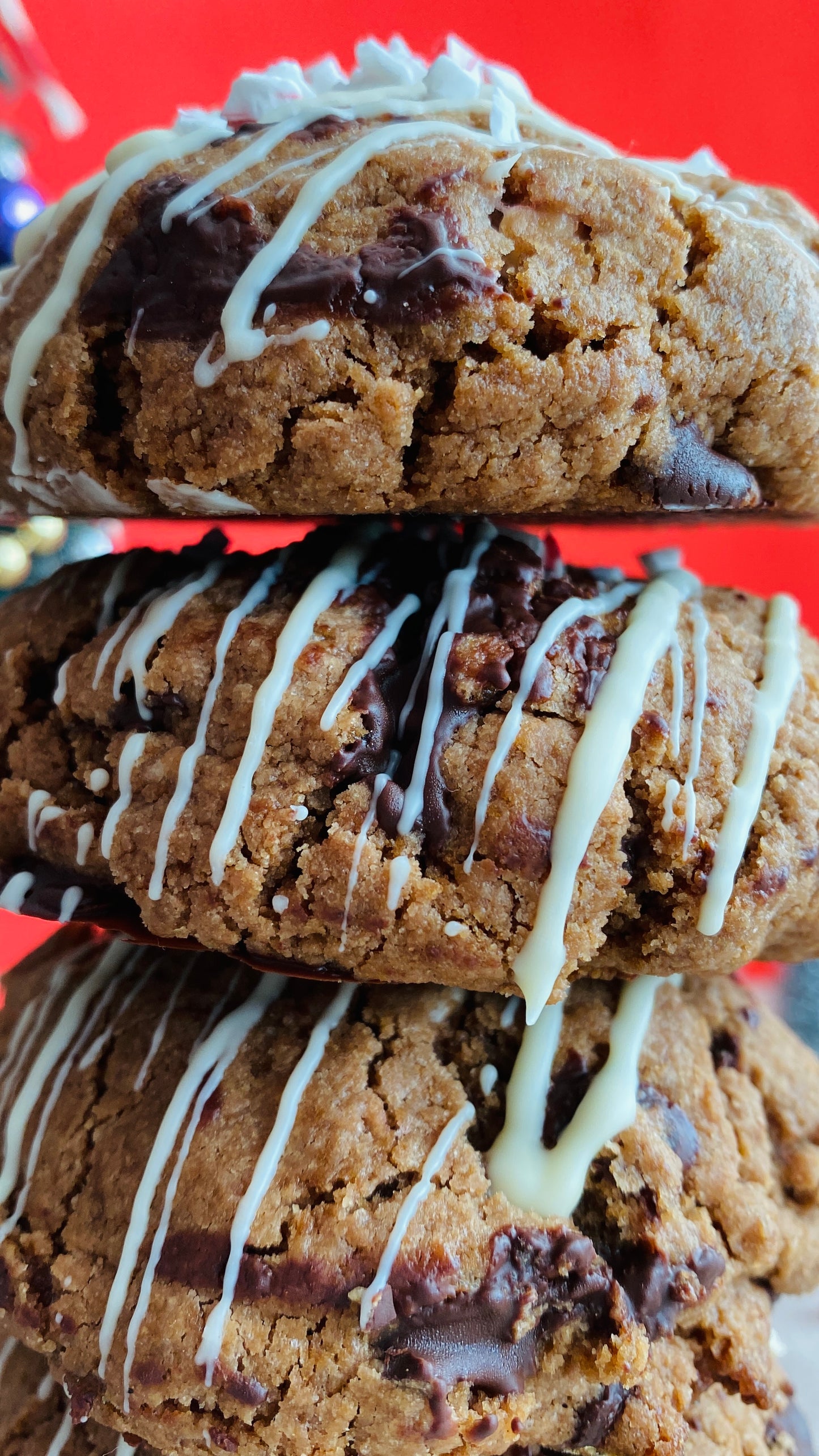 Stack of chocolate chip cookies with white drizzle on a red background