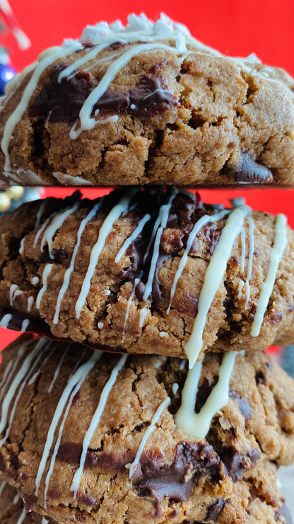 Stack of chocolate chip cookies with white drizzle on a red background