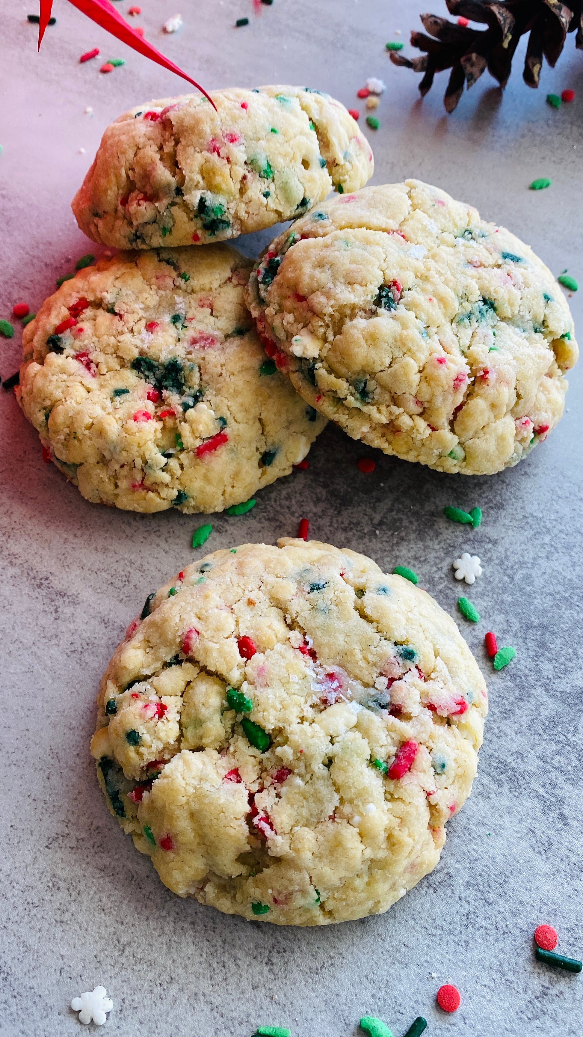 Cookies with colorful sprinkles on a gray surface with Christmas decorations.