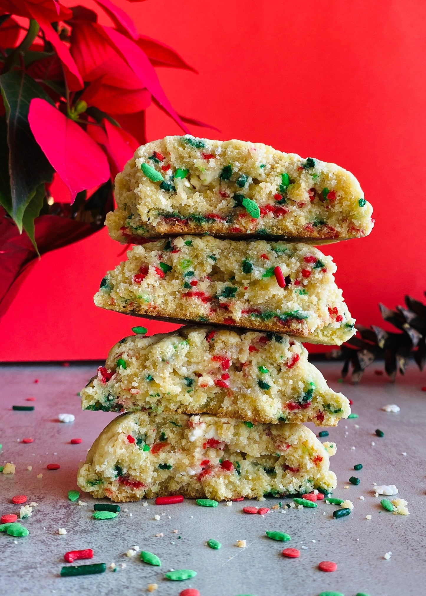 Stack of Christmas-themed cookies with colorful sprinkles against a red background