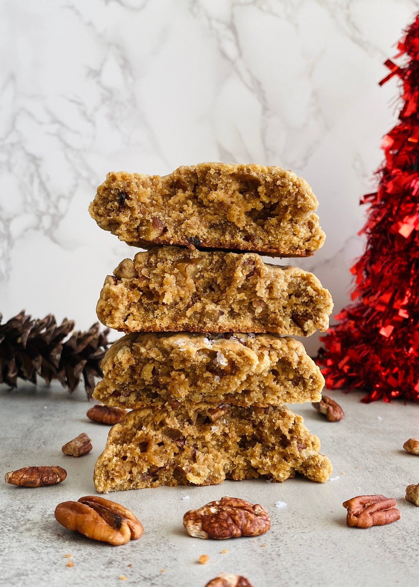 Stack of gingerbread cookies with pine cones and a red decorative item on a light background