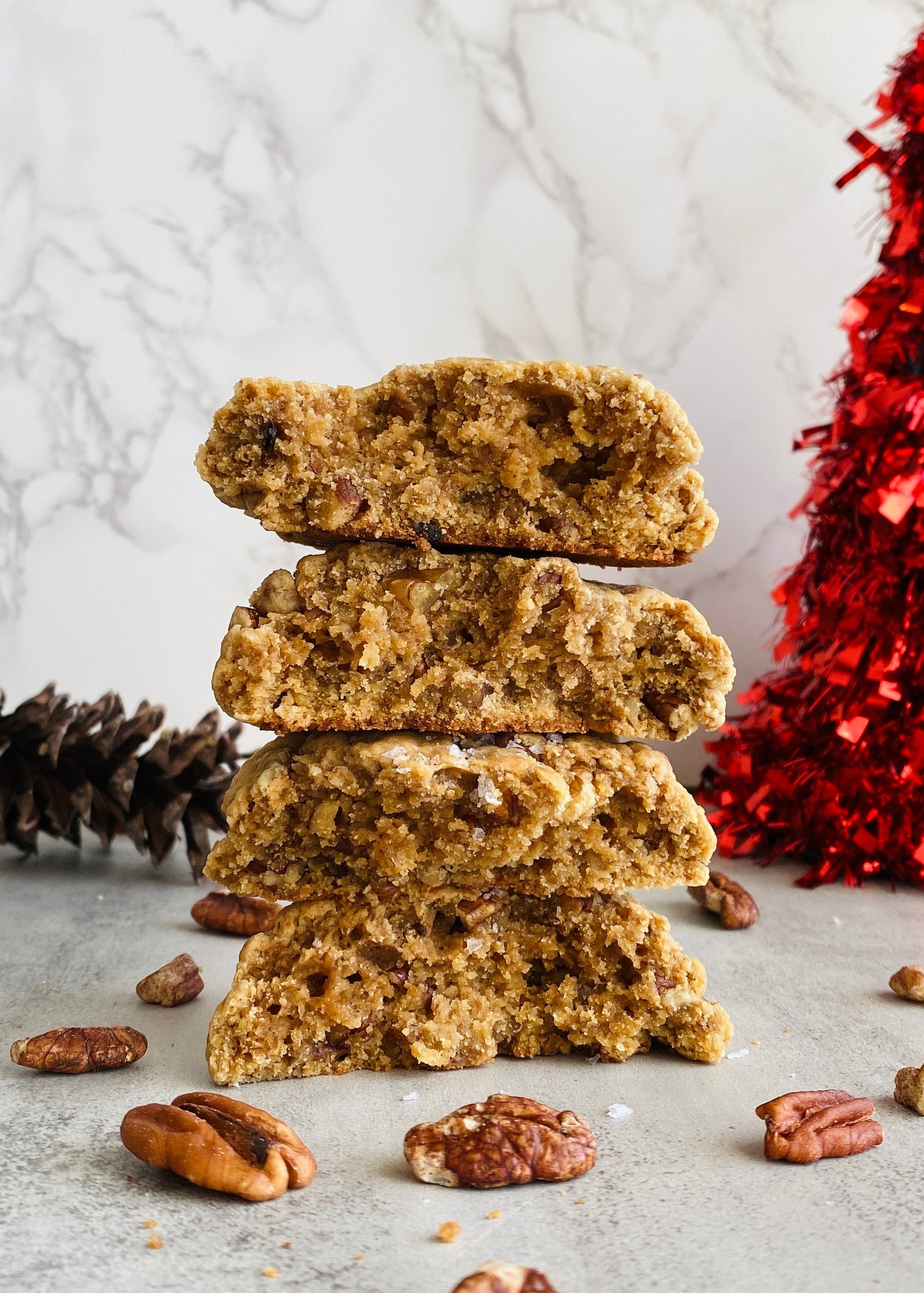 Stack of gingerbread cookies with pine cones and a red decorative item on a light background
